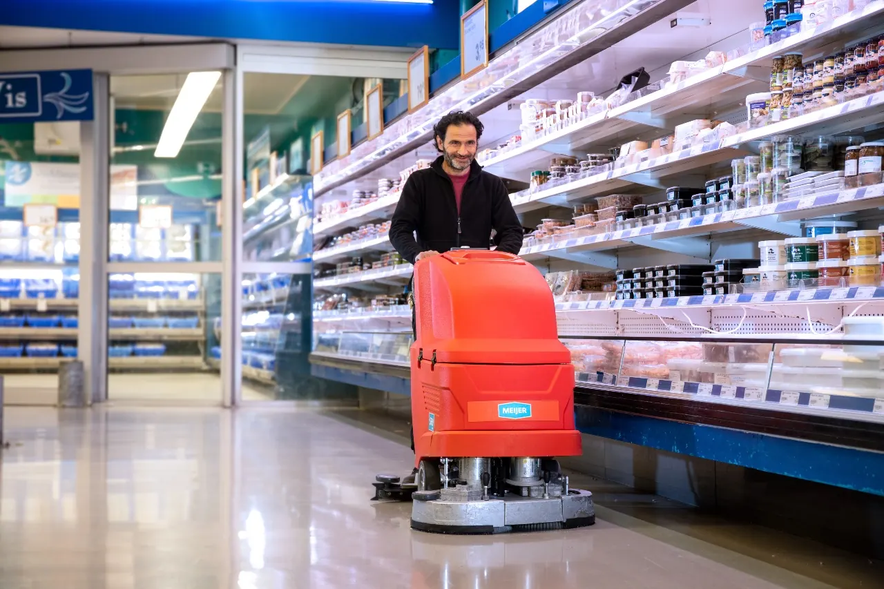 Medewerker met een schrobmachine in een supermarkt