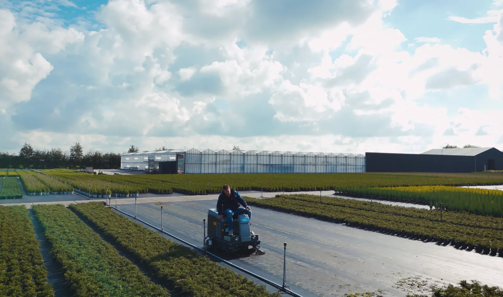 Meijer VR950WD+ veegt worteldoek buiten, met de kassen op de achtergrond