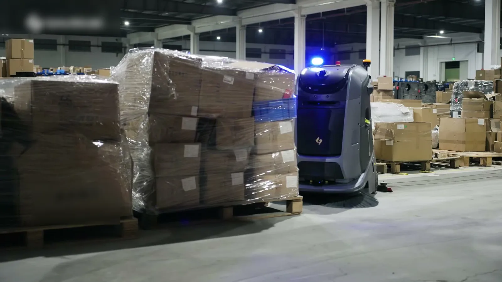 Marvel naast ingepakte pallets in een magazijnhal, met het zwaailicht aan