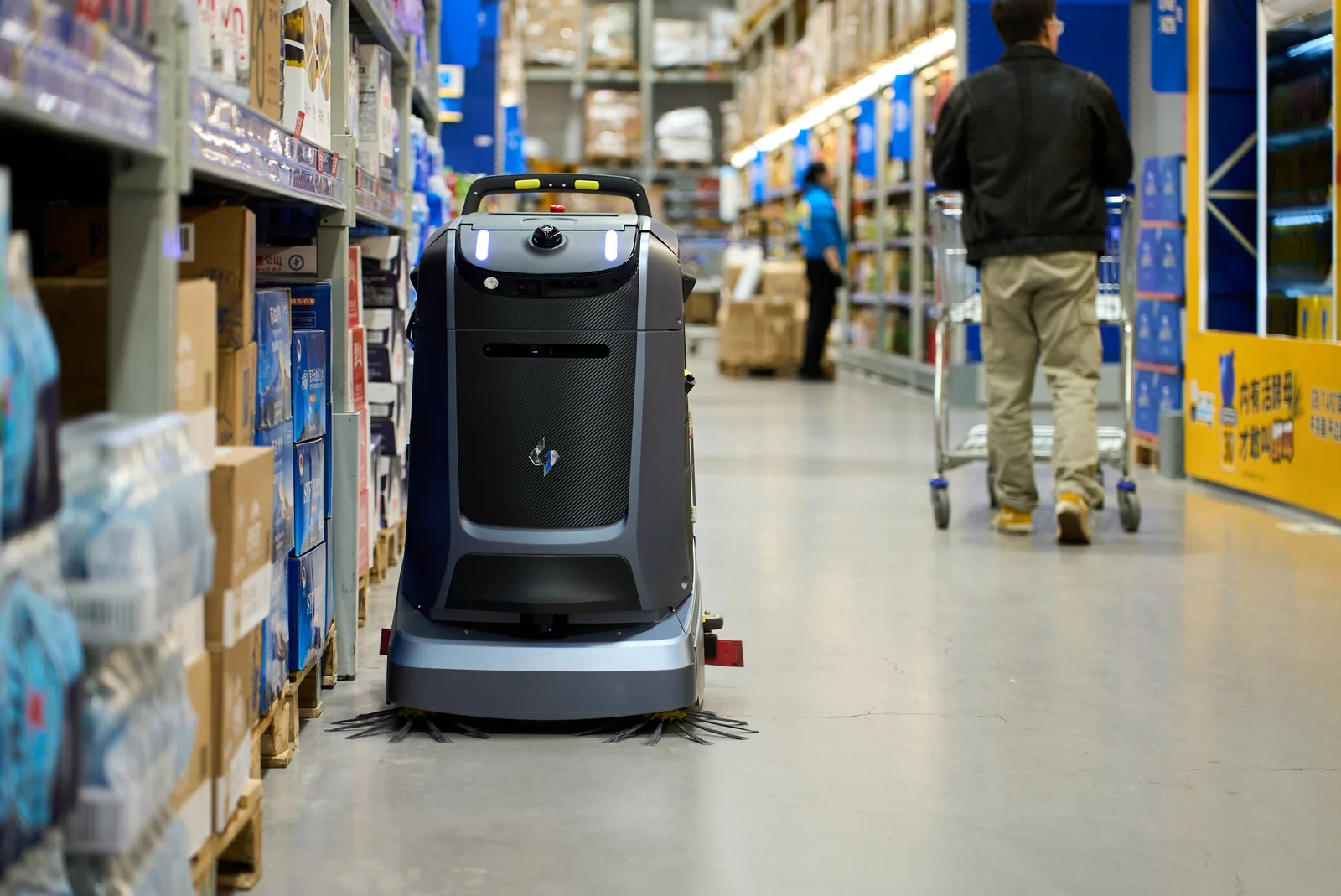 Mira reinigingsrobot in een smal gangpad van een groothandel